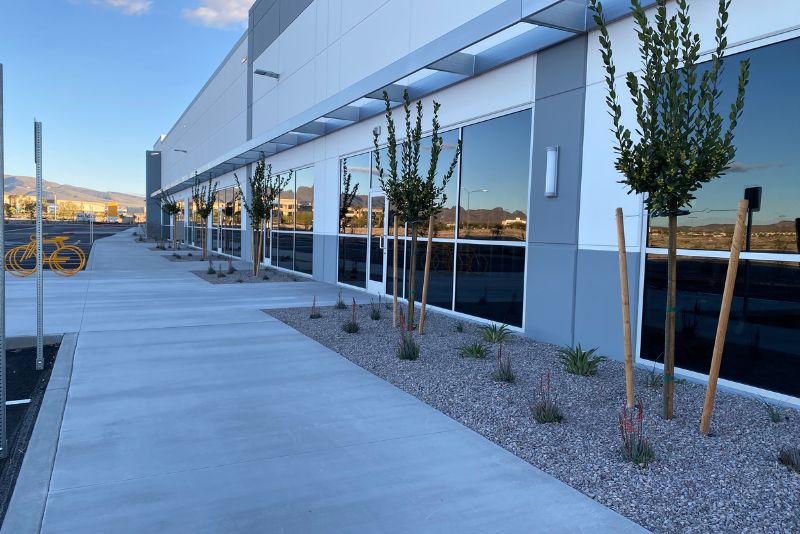 Concrete footpath running alongside a commercial building with landscaped garden beds