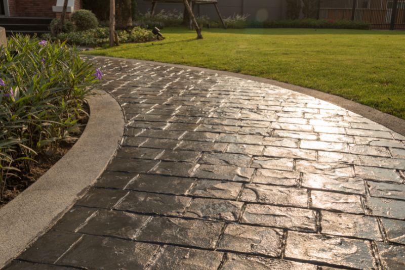 Curved stamped concrete pathway with a decorative cobblestone finish through a garden