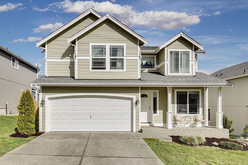 Concrete driveway leading to a double garage at a two-storey home