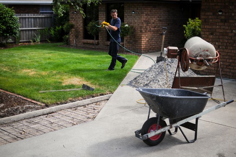 Tradesman preparing a concrete mixer and reinforcement mesh on a residential driveway
