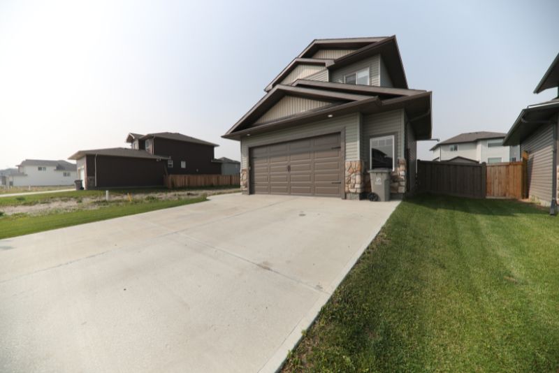 Wide concrete driveway leading to a double garage at a two-storey home