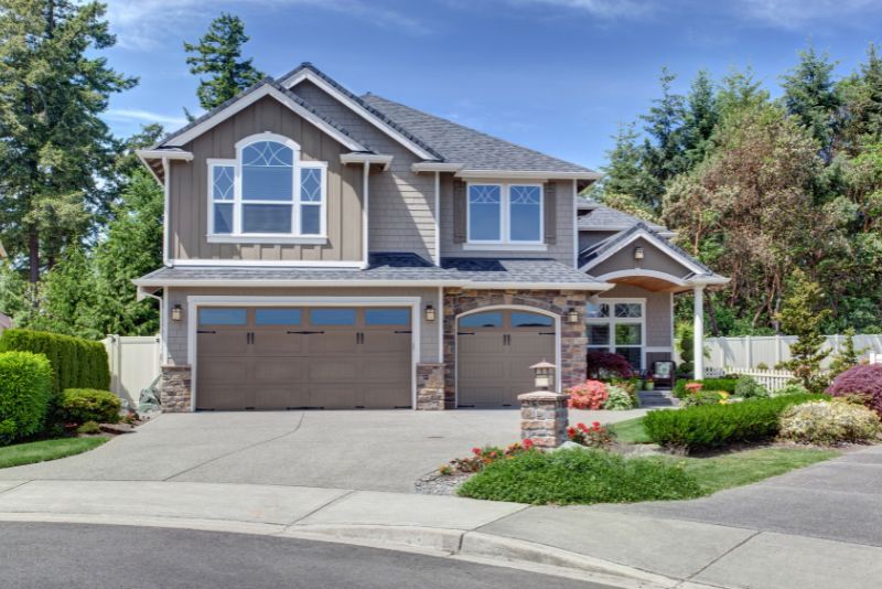 Concrete driveway leading to a triple garage at a two-storey home