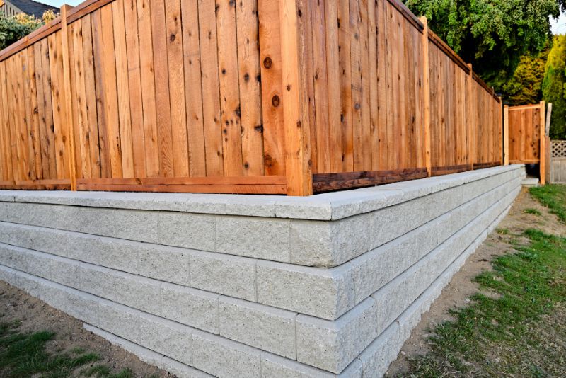 Concrete block retaining wall with a timber fence in a residential backyard